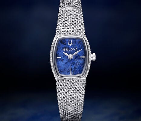 Bulova ladies’ watch with blue marble dial and silver-tone mesh bracelet on dark blue background.